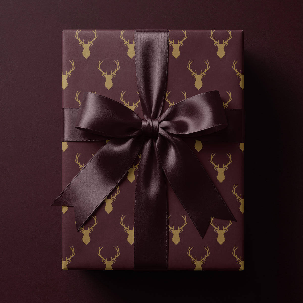 Burgundy reindeer wrapping paper featuring elegant golden antlers