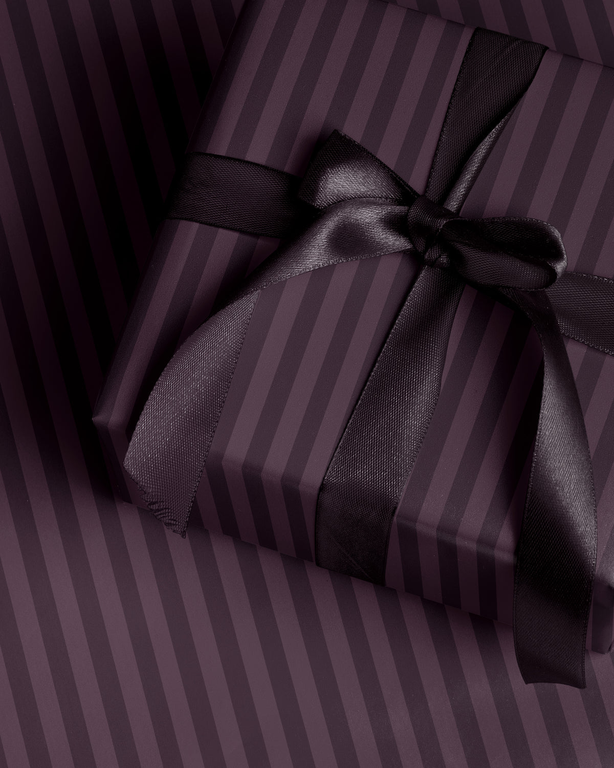 Close-up of plum striped wrapping paper showing the rich purple vertical stripe pattern